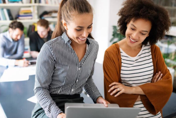 Two women smiling while looking at computer