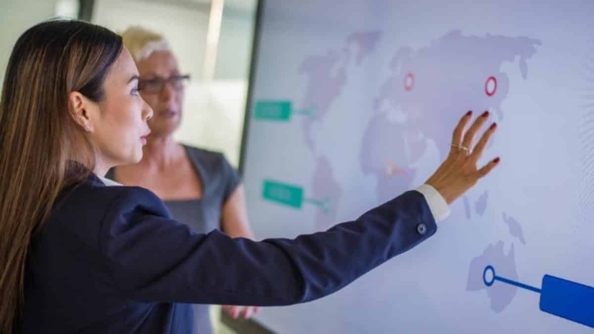two women studying a map on a smart board